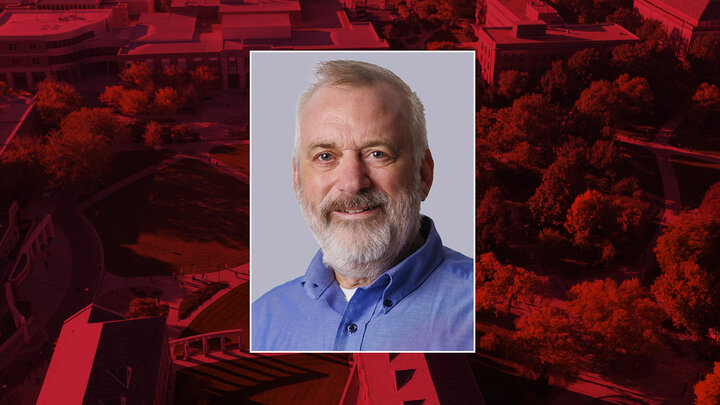 Color portrait of Bob Crisler, director of the Digital Experience Group within University Communication and Marketing, on a red campus background.